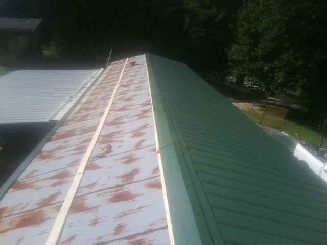 Old rusted panels beside newly installed green metal roofing — Wind Damage Roof Repair by Roofing Brothers in Camino