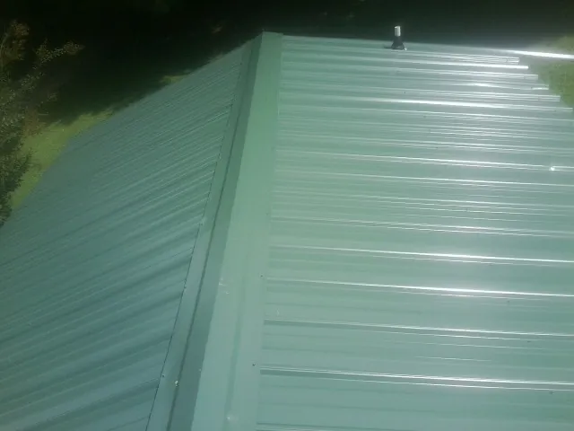 New green metal panels meeting at the ridge of a roof — Flat Roof Repair work by our crew in Camino