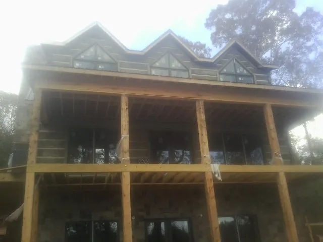 Dormers and porch framing on a large log home under construction — Roof Coating work by our crew in Camino