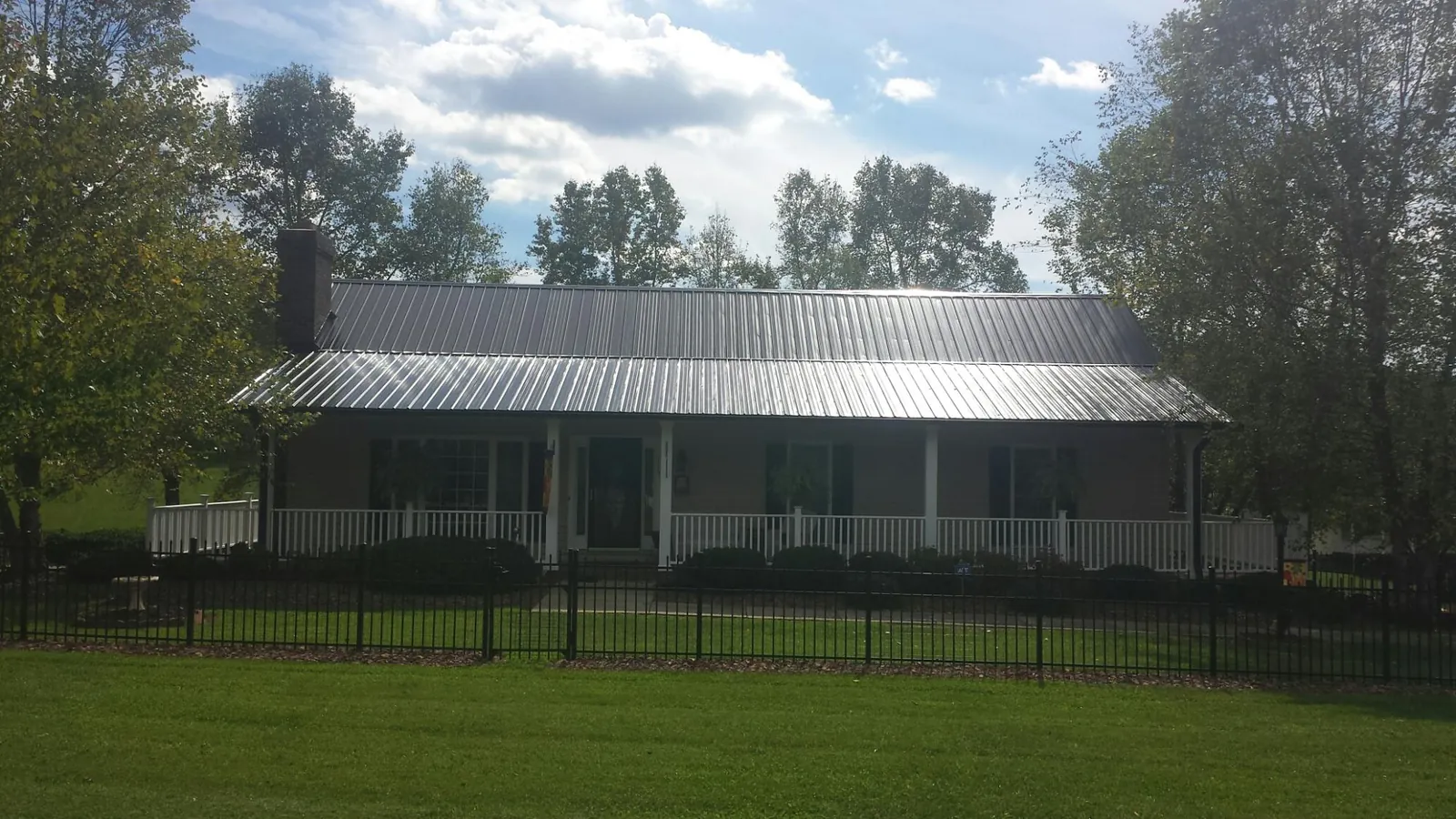 Gray metal roof on a brick ranch with a full width front porch — Gutter Guard Installation work by our crew in Camino