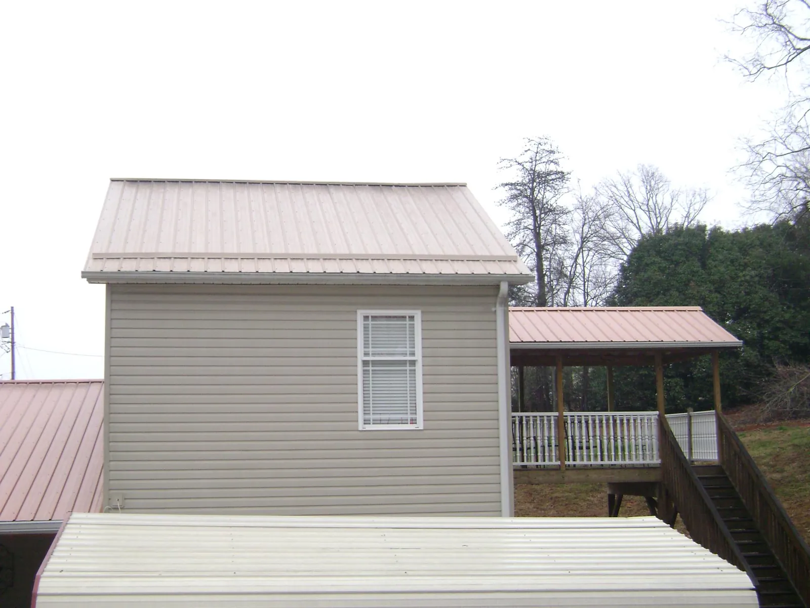 Tan metal roofs on a two story addition and attached porch, from a Roof Replacement job in Camino