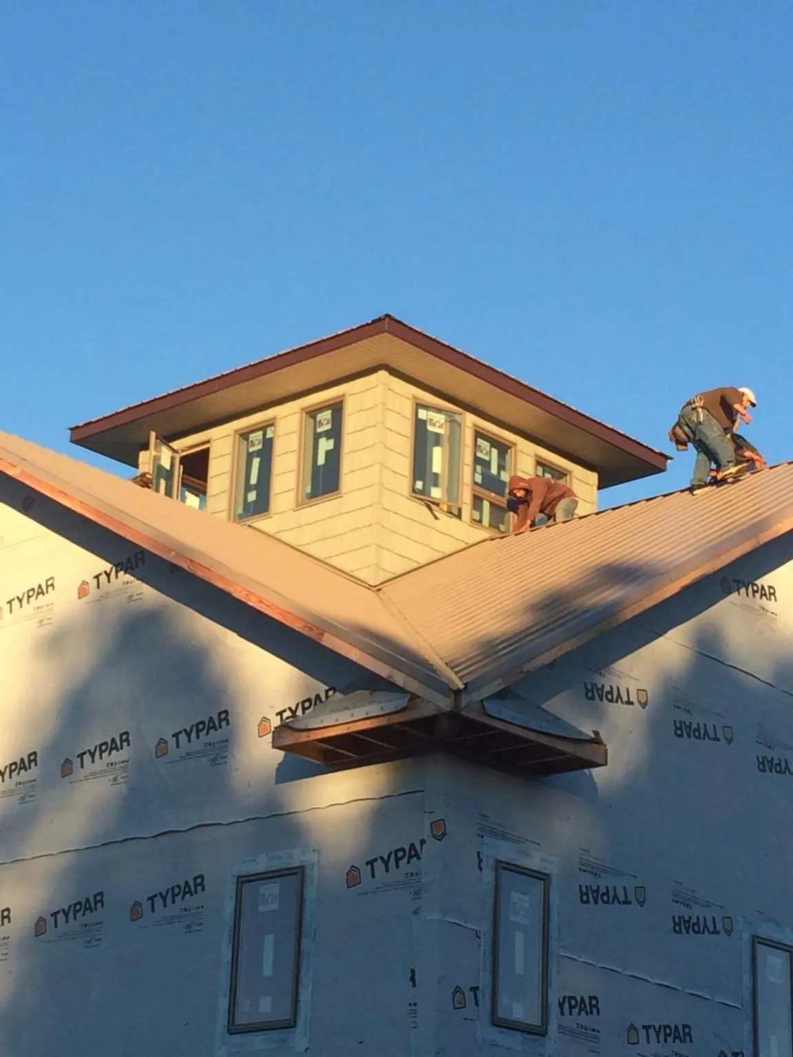 Roofers working around a rooftop cupola on a new metal roof at sunset — Roof Waterproofing in Camino by Roofing Brothers